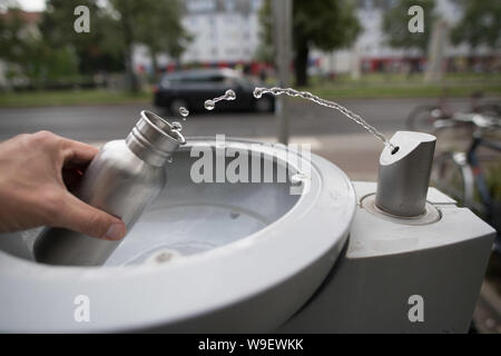 Berlin, Deutschland. 12 Aug, 2019. Ein Passant füllt seine Trinkflasche mit Wasser bei einer Berliner Wasserbetriebe Wasserspender. Quelle: Jörg Carstensen/dpa/Alamy leben Nachrichten Stockfoto