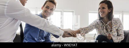 In der breiten Ansicht Bild von drei Geschäftsleute stapeln ihre Hände in Absprache und Zusammenarbeit. Stockfoto