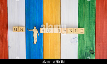 Papier Schneiden Silhouette eines Mannes wegdrücken Buchstaben Un von dem Wort Ungeeignet auf Holz Würfel geschrieben. Über wooden Hintergrund. Stockfoto