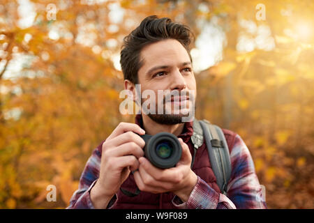 Attraktive kaukasische man Bilder, die mit einer spiegellosen Kamera durch den Wald im Herbst in Kanada Stockfoto