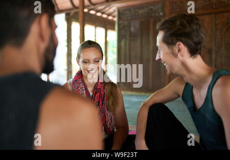 Candid shot von drei verschiedenen Freunden gemeinsam diskutieren nach Yoga Klasse in traditionellen Tempel auf Bali, Indonesien Stockfoto