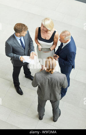 Hohe Betrachtungswinkel von Geschäftsleuten die Arbeit mit Dokumenten und digitalen Tablet und reden miteinander im Büro Stockfoto