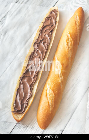 Die Hälfte der Baguette mit Schokoladencreme auf dem hölzernen Tisch Stockfoto