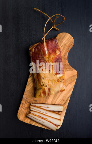 Geräuchertes Fleisch. Schmackhafte Speck auf Schwarzen Tisch. Ansicht von oben. Stockfoto