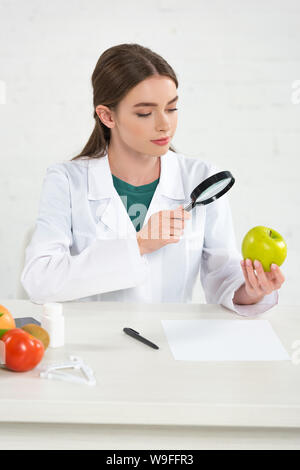 Ernährungsberater in weißen Mantel suchen bei Apple durch die Lupe Stockfoto