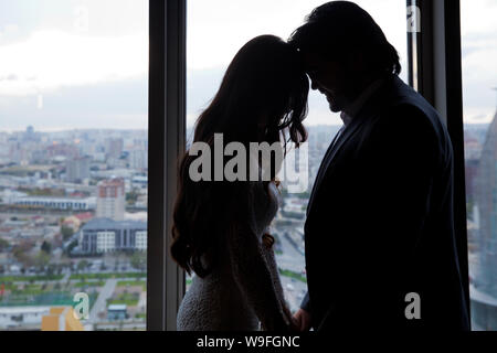 Silhouette der Braut schöne junge Frau und Bräutigam schöner Mann teilen Liebe Kopf auf den Hintergrund des Fensters zu Kopf. Die Braut und der Bräutigam in einem gemütlichen Haus Stockfoto