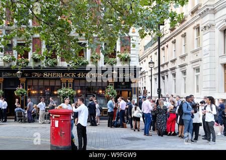 Menschenmassen genießen Sie einen Sommer Drink am Abend außerhalb des Sherlock Holmes Public House auf der Northumberland Street, Central London England Großbritannien Stockfoto