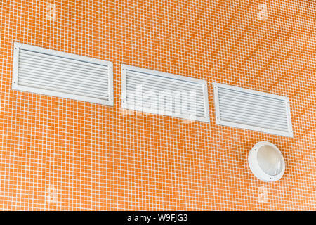 Vent Gitter mit weißen Fensterläden auf der Orange Fliesen am Pool an der Wand. Stockfoto