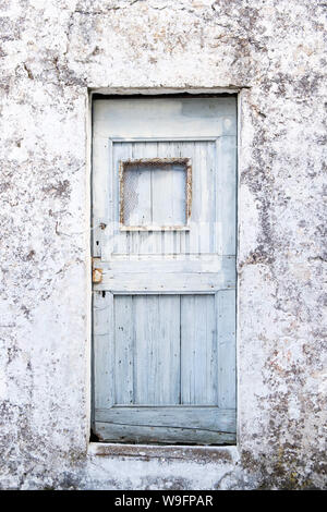 Ein helles Blau Holztür in einem zerbröckelnden Fassade in das verlassene Dorf Drakopoulata in Kefalonia, Griechenland. Stockfoto