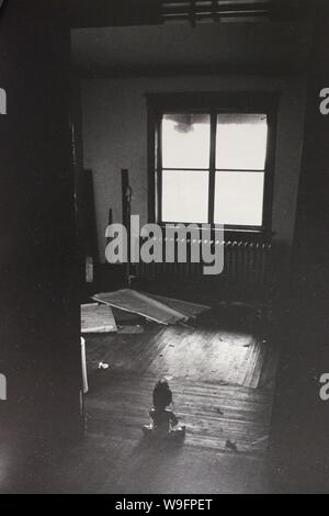 Feine schwarze und weiße Kunst Fotografie von den 1970er Jahren von einer Puppe Blick aus dem Fenster eines alten, verlassenen Landhaus. Stockfoto