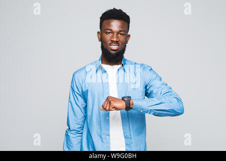 Welche Zeit ist es. Porträt der jungen attraktiven Mann mit dunklen afro Frisur im weißen T-Shirt und rote shirt an Hand Watch zeigt mit glücklichen Gesicht expre Stockfoto