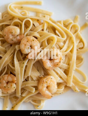 Garnelen Garnelen scampi a Knoblauch gewürzt in Butter, auf Fettuccine Pasta serviert. Weiße Platte, Nahaufnahme. USA. Stockfoto
