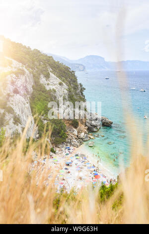 (Selektive Fokus) Ansicht von oben, atemberaubenden Blick auf einen wunderschönen Strand mit Sonnenschirmen und Menschen zum sonnenbaden und schwimmen im türkisblauen Wasser. Stockfoto