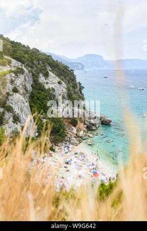 (Selektive Fokus) Ansicht von oben, atemberaubenden Blick auf einen wunderschönen Strand mit Sonnenschirmen und Menschen zum sonnenbaden und schwimmen im türkisblauen Wasser. Stockfoto