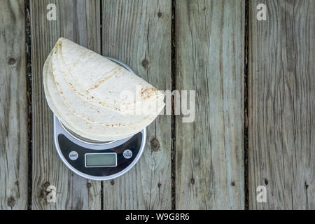 Low carb Tortillas auf einer Skala auf Holzuntergrund - Trendanalyse Gesundheit Nahrung. Draufsicht von oben. Keto freundlich. Leeren leeren Raum für Text oder Kopie sp Stockfoto