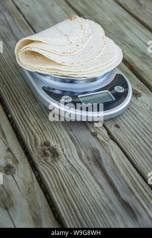 Low carb Tortillas auf einer Skala auf Holzuntergrund - leerer leeren Raum für Text oder kopieren. Eine tortilla wenig Kohlenhydrate, die passt in die Keto Stockfoto