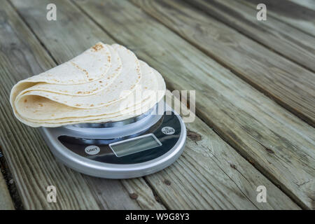 Low carb Tortillas auf einer Skala auf Holzuntergrund - leerer leeren Raum für Text oder kopieren. Eine tortilla wenig Kohlenhydrate, die passt in die Keto Stockfoto