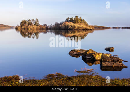 In den stillen Wassern des Lough Corrib, County Galway, Irland ist die Reflexion über die umliegenden Berge und Inseln bei Sonnenuntergang Stockfoto