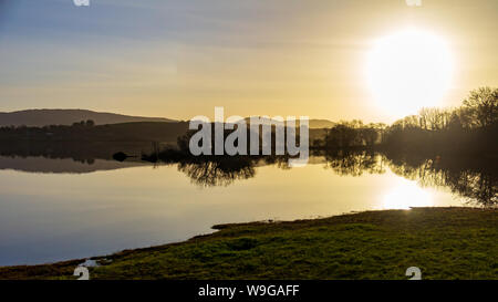 In den stillen Wassern des Lough Corrib, County Galway, Irland ist die Reflexion über die umliegenden Berge und Inseln bei Sonnenuntergang Stockfoto