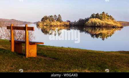 In den stillen Wassern des Lough Corrib, County Galway, Irland ist die Reflexion über die umliegenden Berge und Inseln bei Sonnenuntergang Stockfoto