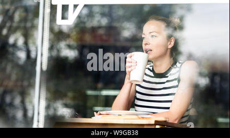 Junge kaukasier Frau alleine sitzen im Café nachdenklich lehnte sich auf ihre Hand und schaute durch das Fenster Stockfoto