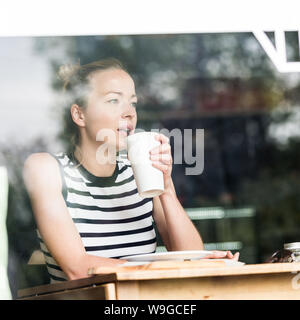 Junge kaukasier Frau alleine sitzen im Café nachdenklich lehnte sich auf ihre Hand und schaute durch das Fenster Stockfoto