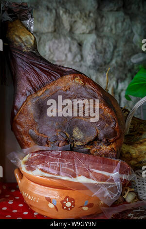 Ganzen Schinken mit Knochen Bein des montenegrinischen Njeguski prsut Schinken ähnlich wie Schinken und geschnittenes verpacktes Fleisch auf dem Markt in Kotor, Montenegro Stockfoto