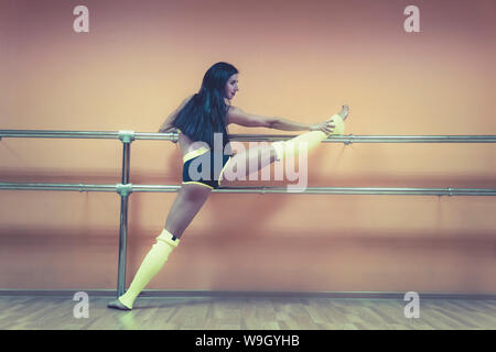 Schöne junge Tänzer ihre Flexibilität in der Nähe von ballet Barre auf leer Dance Hall Hintergrund. Seitliche Sicht auf attraktive sportliche Mädchen Stockfoto