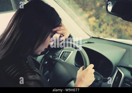 Frau Treiber Gefühl Angst hinter dem Lenkrad. Nahaufnahme des weinenden Mädchen im Fahrzeug sitzen und weinen. Fahrerin hatte Kopfschmerzen und Übelkeit Stockfoto