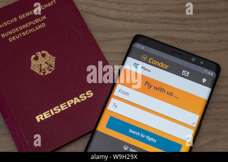 Deutschen Pass und Condor Airlines Website auf einem Smartphone gesehen, während auf einem hölzernen Tisch gelegt. Stockfoto