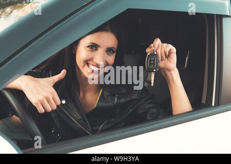 Schönes Auto fahrer lächelnde Frau mit neuen Autoschlüssel und Auto. Kaukasische Mädchen sitzen im Auto, lächelnd und demonstrieren. Besitzerin von Stockfoto