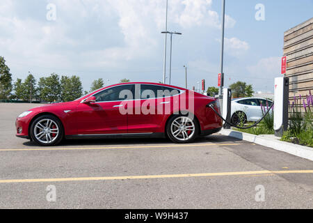 Red Tesla Model S Plug-in, das Aufladen bei Tesla Urban Kompressor. Stockfoto