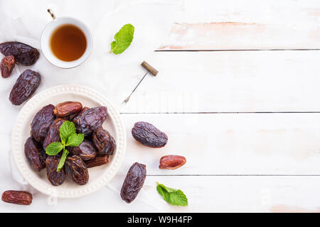 Ramadan Essen und Getränke Konzept. Tee mit Termine Obst und Minze auf einem weißen Tisch Hintergrund. Ansicht von oben, flach. Stockfoto