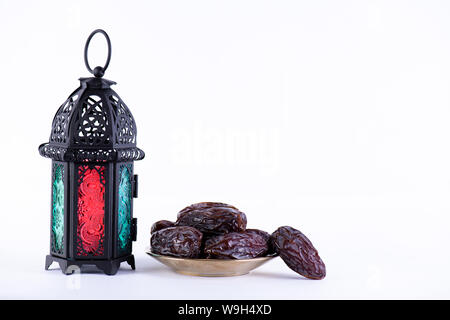 Ramadan Essen und Getränke Konzept. Ramadan Laterne mit arabischen Lampe, Holz Rosenkranz, Termine Obst und Beleuchtung auf weißem Hintergrund. Stockfoto