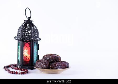 Ramadan Essen und Getränke Konzept. Ramadan Laterne mit arabischen Lampe, Holz Rosenkranz, Termine Obst und Beleuchtung auf weißem Hintergrund. Stockfoto