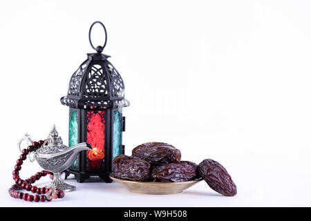 Ramadan Essen und Getränke Konzept. Ramadan Laterne mit arabischen Lampe, Holz Rosenkranz, Termine Obst und Beleuchtung auf weißem Hintergrund. Stockfoto