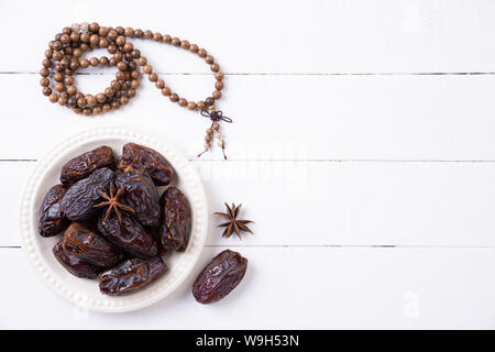 Ramadan Essen und Getränke Konzept. Holz Rosenkranz, Milch und Obst auf einem weißen Tisch Hintergrund. Ansicht von oben, flach. Stockfoto