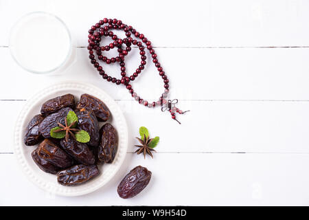 Ramadan Essen und Getränke Konzept. Holz Rosenkranz, Milch und Obst auf einem weißen Tisch Hintergrund. Ansicht von oben, flach. Stockfoto