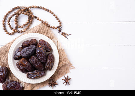Ramadan Essen und Getränke Konzept. Holz Rosenkranz, Milch und Obst auf einem weißen Tisch Hintergrund. Ansicht von oben, flach. Stockfoto