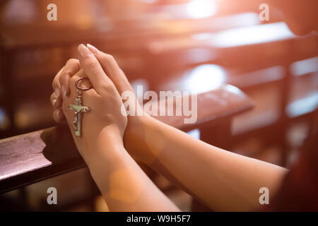 Frau hand Rosenkranz gegen Kreuz und beten zu Gott in der Kirche. Stockfoto