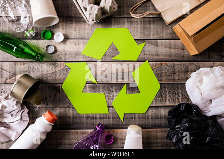 Blick von oben auf die verschiedenen Müll Materialien mit Recycling Symbol auf Tisch Hintergrund. Recycling, Umwelt und Eco-Konzept Stockfoto