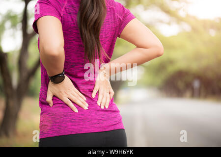 Junge asiatische Frau Schmerzen auf dem Rücken und der Hüfte beim Trainieren, health care Konzept. Stockfoto