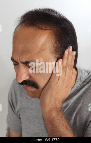 Reifer Mann, der Ohren mit Händen bedeckt Stockfoto