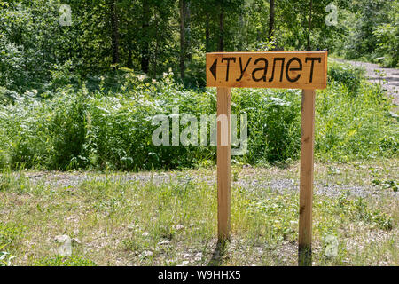 Holzschild mit einem Zeiger im Wald mit der Inschrift in der Russischen wc Stockfoto