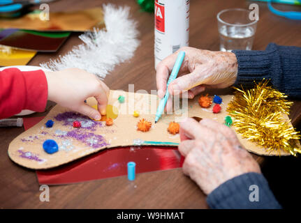 Schulkinder in der Bristol besuchen Pflegeeinrichtungen zu Weihnachten Dekorationen machen mit Bewohnern in einer Regelung, die von der Nächstenliebe lebendig Aktivitäten organisiert Stockfoto