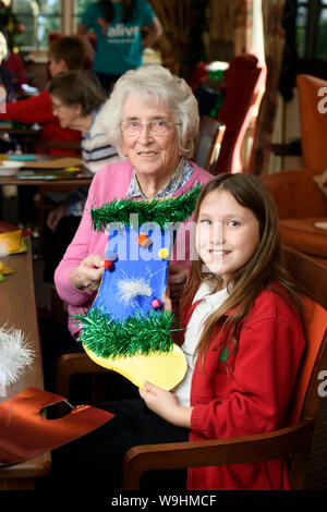 Schulkinder in der Bristol besuchen Pflegeeinrichtungen zu Weihnachten Dekorationen machen mit Bewohnern in einer Regelung, die von der Nächstenliebe lebendig Aktivitäten organisiert Stockfoto