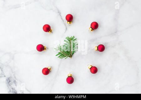 Stilisierte Weihnachten aus Tannen Zweig und roten Ball Spielzeug auf Marmor Hintergrund. Neues Jahr und Weihnachten feiern. Flach, oben vie Stockfoto