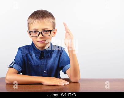 Banner Schüler mit einem blauen Hemd am Tisch sitzen. Junge mit Brille auf weißem Hintergrund. Konzept Zurück zur Schule Stockfoto
