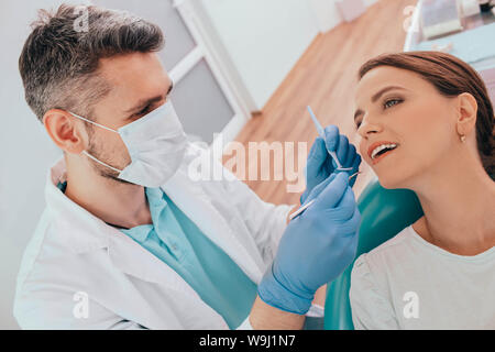 Frau erhalten Plaque-Entfernung mit zahnmedizinischen Ausrüstung durch ihre Zahnärzte an der Klinik Stockfoto