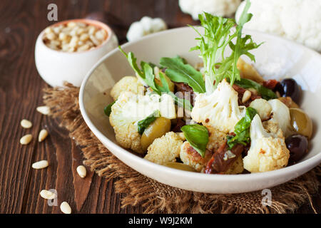 Gebratener Blumenkohl mit Oliven, getrocknete Tomaten, Pinienkernen und Basilikum. Gesunde Ernährung Stockfoto